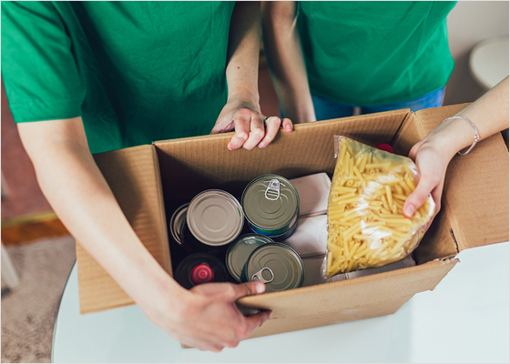 Volunteers stacking food in a box.