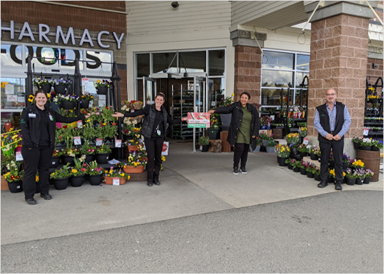 Des employés de Thrifty Foods remettent des cartes-cadeaux aux clients en respectant la distanciation physique.